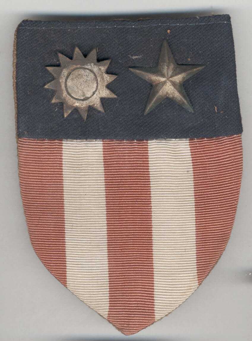 United States Army Air Forces China-Burma-India (CBI) Theater Shoulder Sleeve Insignia; shield shaped insignia with blue felt top field with applied silver Nationalist Chinese star and five point American star; red and white embroidered stripes on lower field. Collection of the National Air & Space Museum.