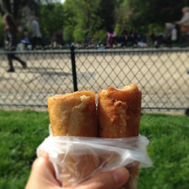 A hand holds two lumpia in a plastic bag.